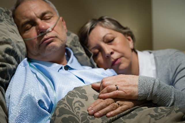 Protect your assets before entering into a nursing home: ill husband in bed with wife nursing him