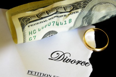 Divorce costs money. Picture of $100 American bill and a gold wedding ring.