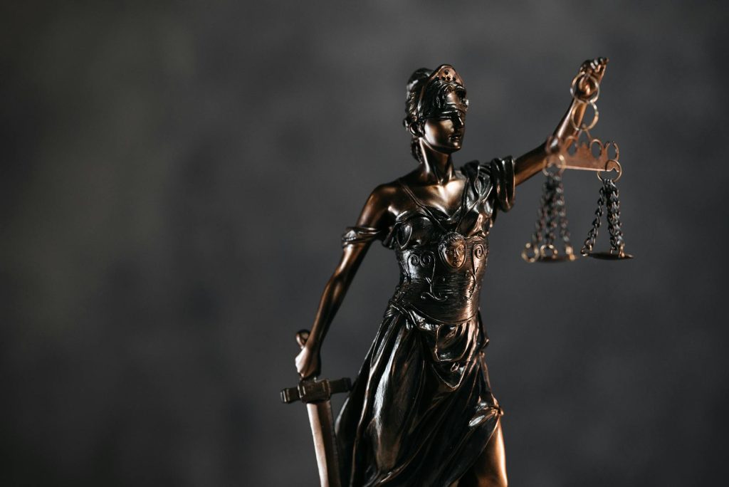 detailed bronze lady justice statue with scales and sword against a dark background, symbolizing law and justice showing what assets are protected strategy for high-net-worth
