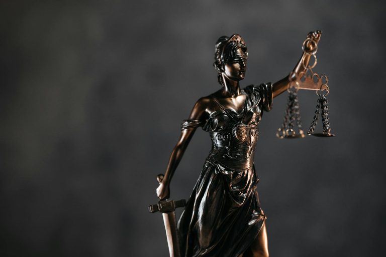 detailed bronze lady justice statue with scales and sword against a dark background, symbolizing law and justice showing what assets are protected strategy for high-net-worth