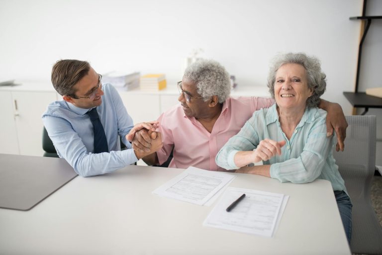 senior couple in office meeting with consultant, discussing financial documents and smiling showing how to set up strategy for high-net-worth individuals considering irrevocable trust asset